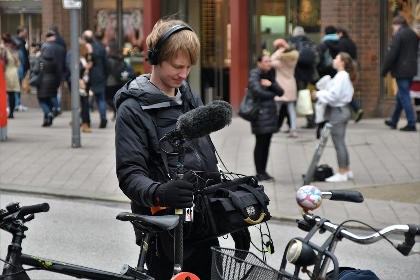 Man in headphones records audio on a city sidewalk.