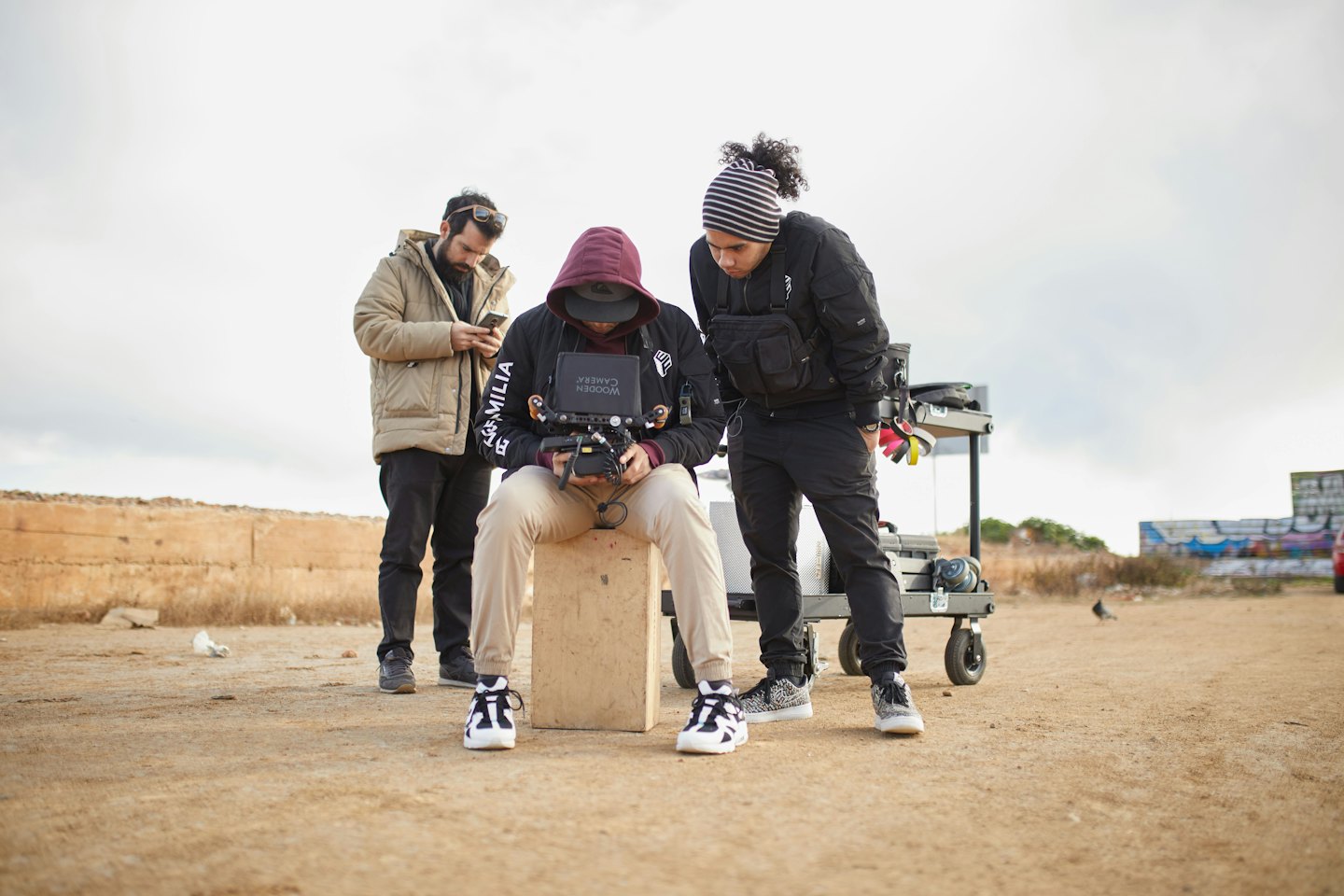 Film crew reviews footage on a monitor outdoors.