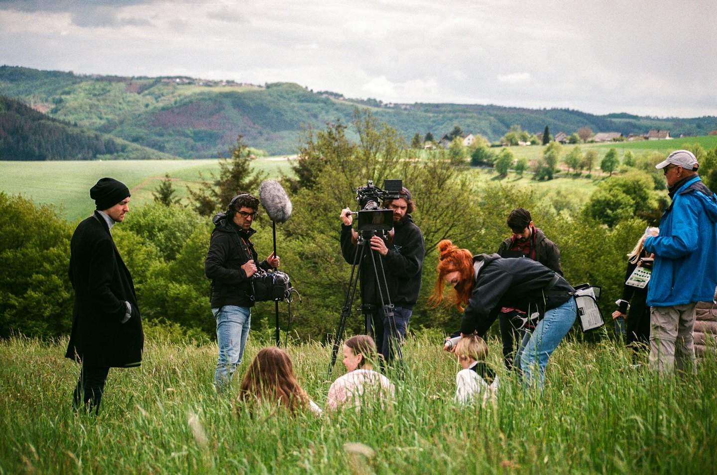 Film crew filming a scene in a grassy meadow.