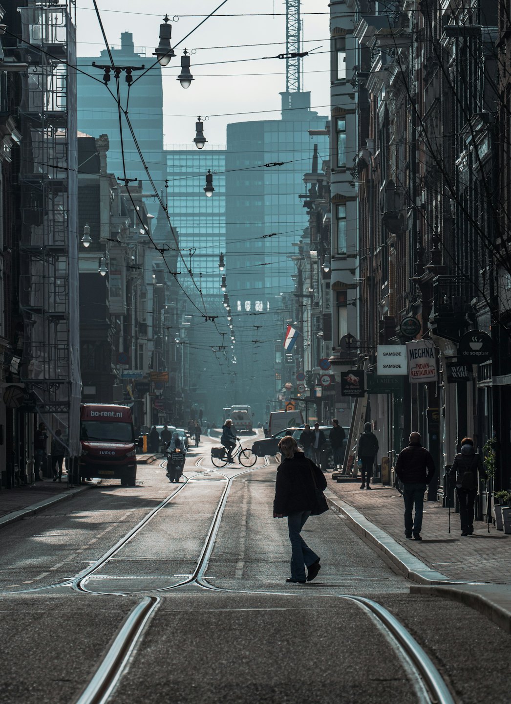 Pedestrians and a delivery van travel along a busy city street.